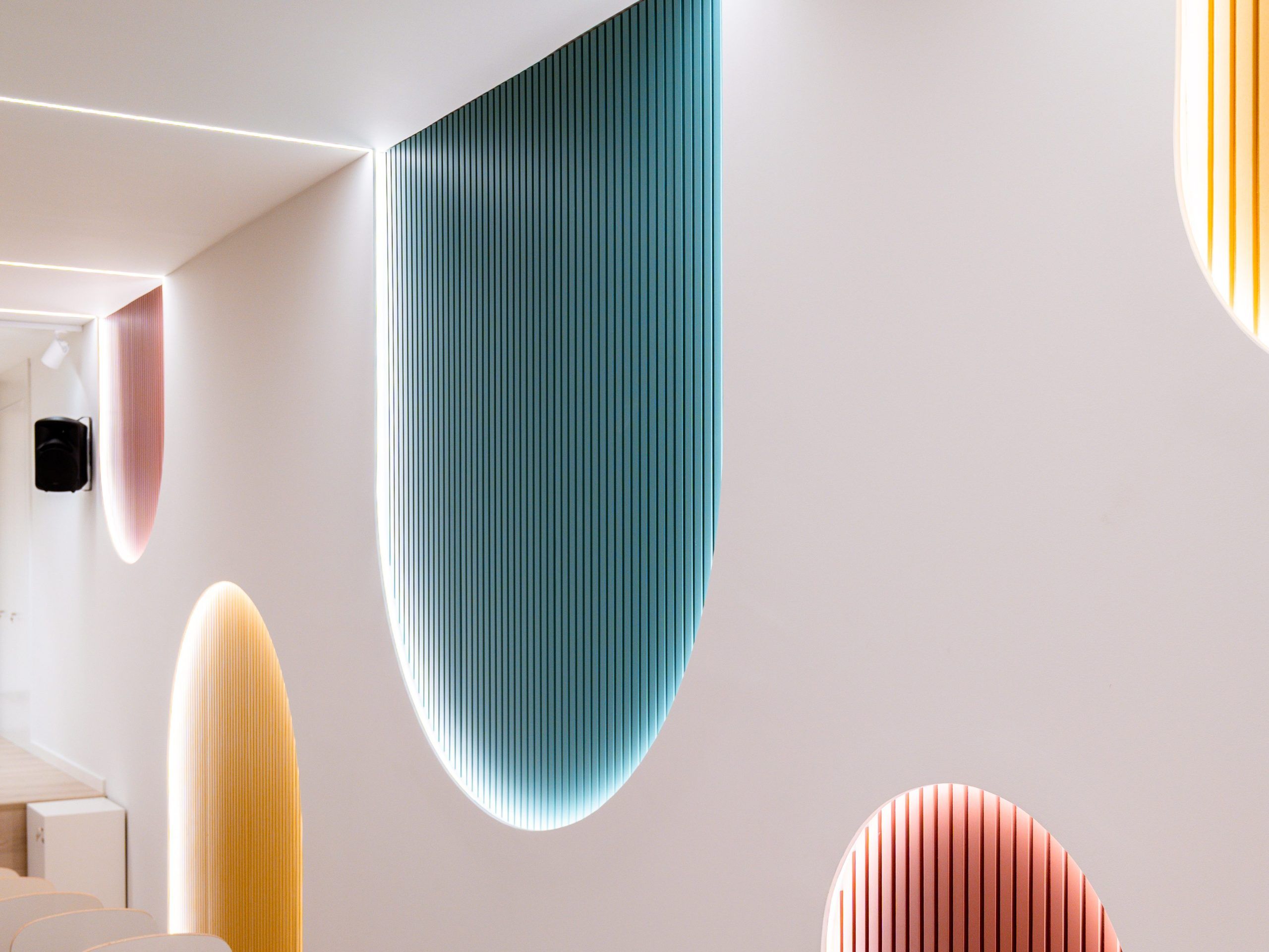Textura y bienestar en un espacio escolar con paneles de color iluminados.